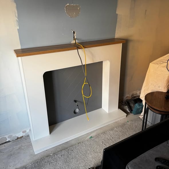 The fireplace surround mid build, bare walls and loose cables